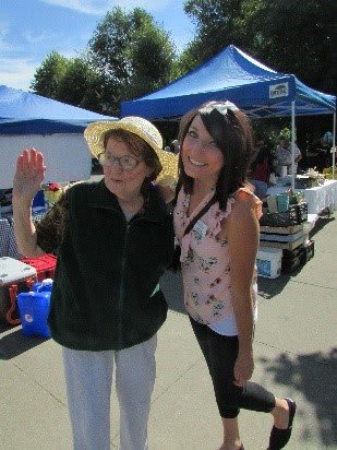 Two people posing together at an outdoor market.