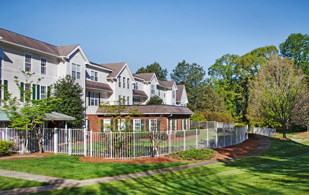 A residential building with a white exterior, surrounded by trees and a well-maintained lawn.