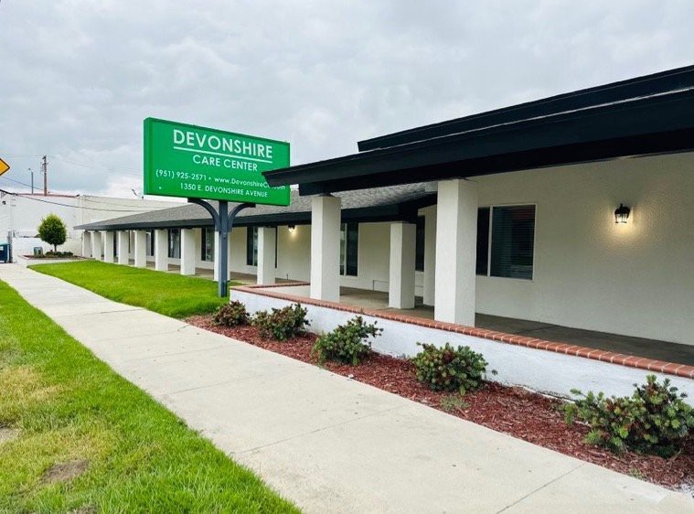 A healthcare clinic with a prominent green sign and manicured landscaping.