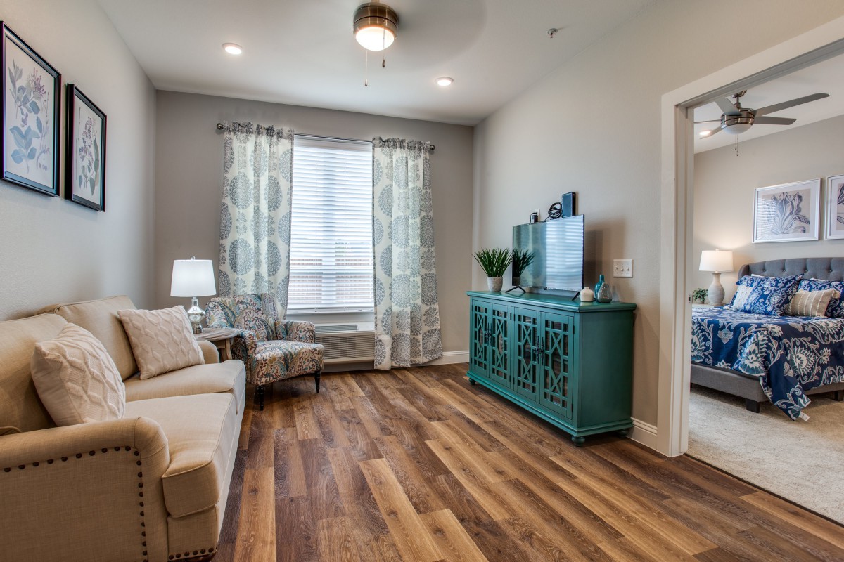 A cozy living room with modern decor, featuring a hardwood floor, a comfortable sofa and armchair, and a stylish cabinet.