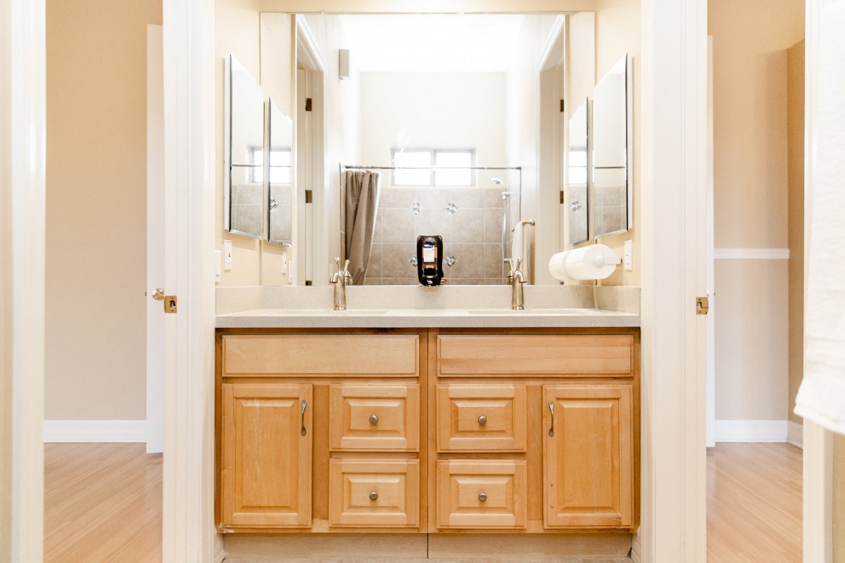 A bathroom vanity with dual sinks and mirrors, featuring wooden cabinets.