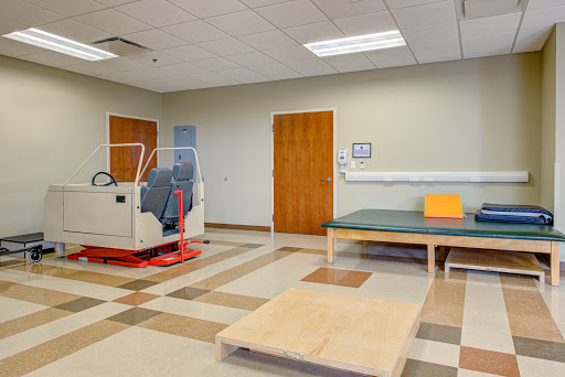 A spacious physical therapy room equipped with exercise equipment and a rehabilitation mat.