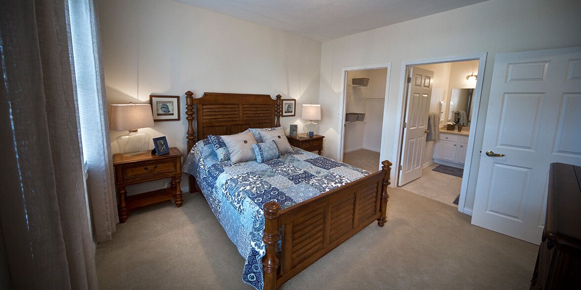 A cozy bedroom featuring a wooden bed frame with blue and white patterned bedding and matching nightstands.