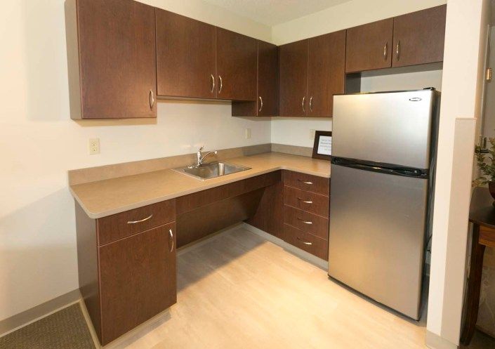 Modern kitchen with wooden cabinets and stainless steel fridge.