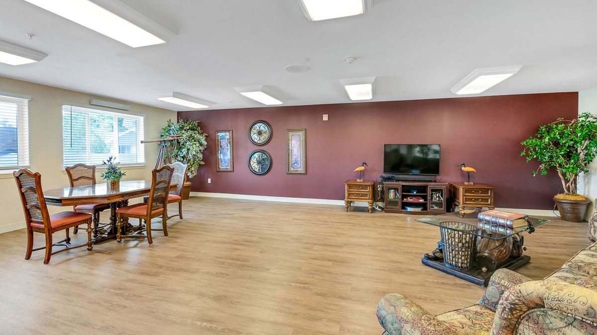 A spacious living room featuring hardwood floors, a wall-mounted television, and stylish decor.