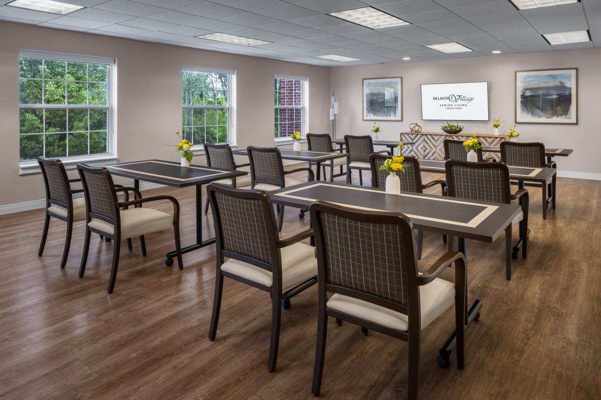 A well-organized classroom or conference room with tables and chairs arranged neatly, featuring a presentation screen and decorative flowers on the tables.