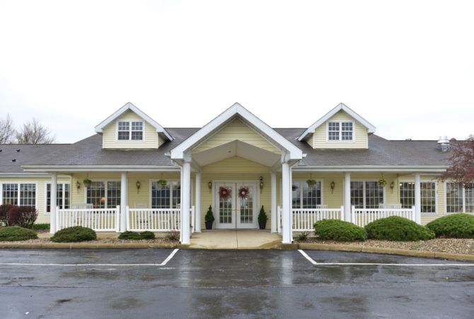 A residential style building with a porch and roof windows, situated next to a parking lot.