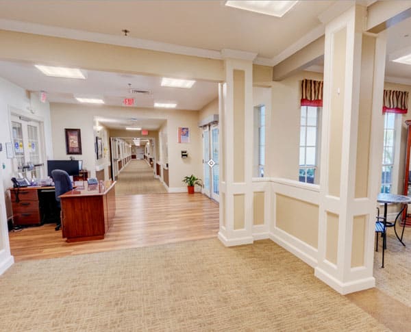 A spacious office hallway with a desk and warm lighting.