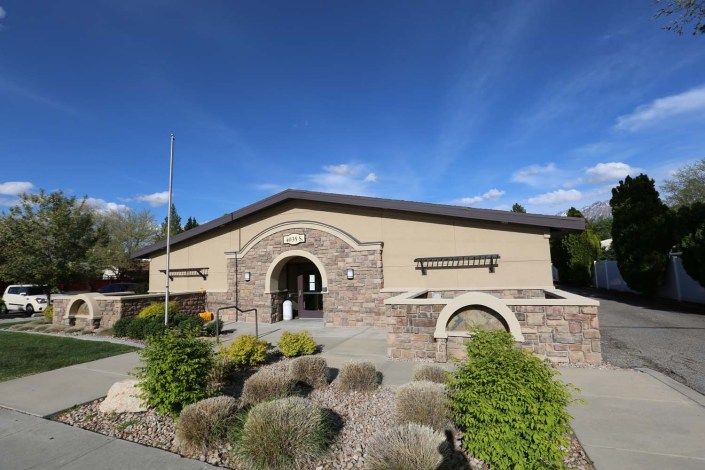 A beautifully designed building with stone accents and lush landscaping under a clear blue sky.