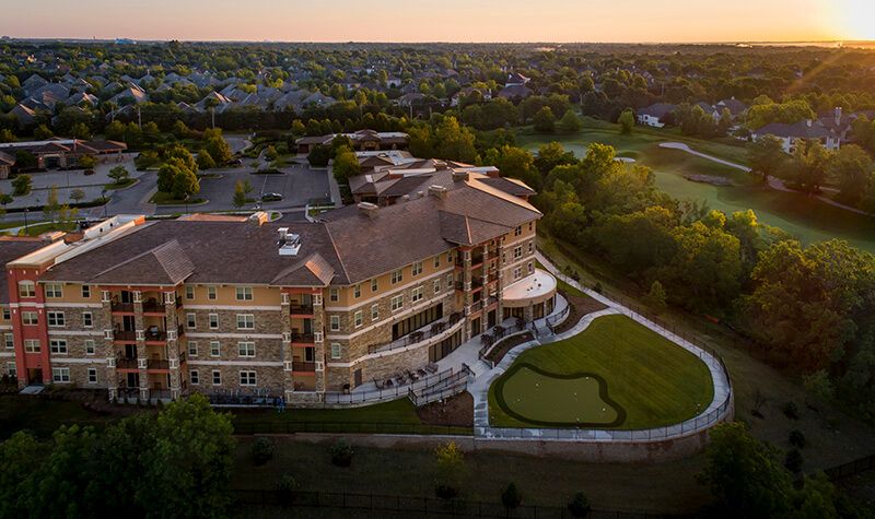 Aerial view of a large building surrounded by greenery at sunset.