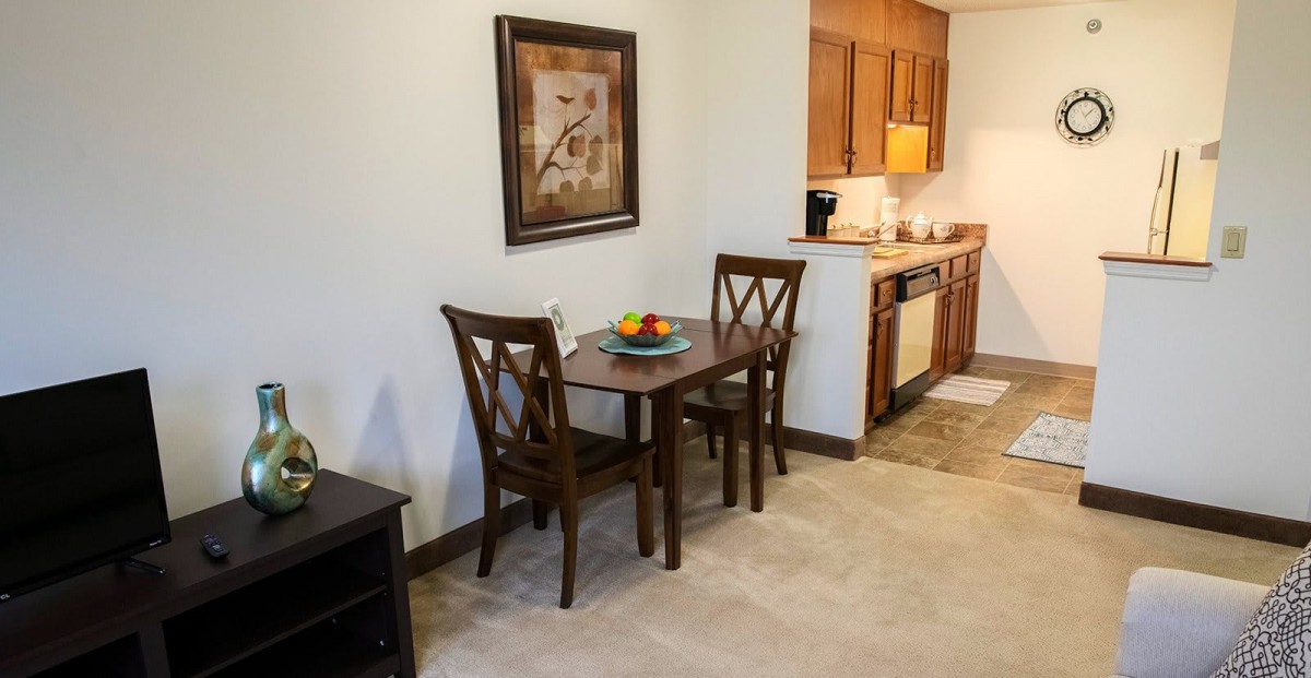 A cozy dining area with a wooden table and two chairs located next to a compact kitchen.