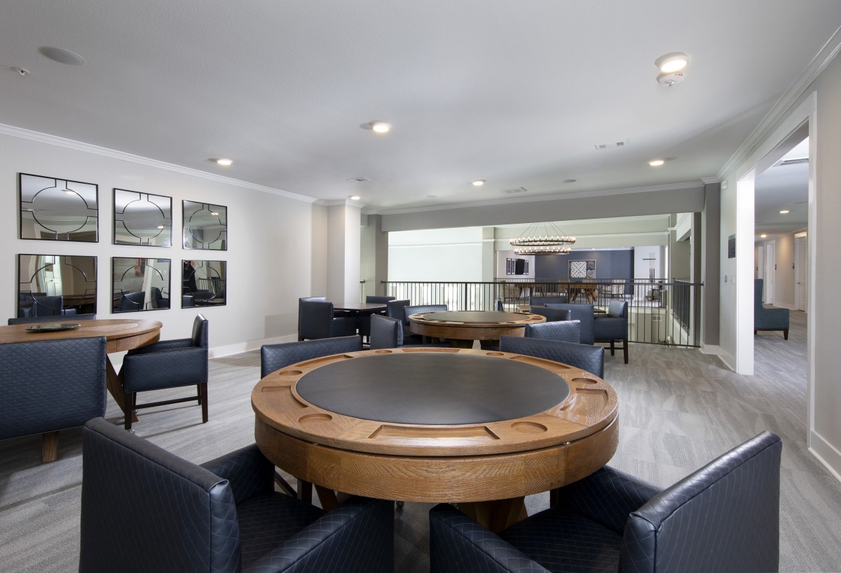 A modern game room featuring a round poker table surrounded by comfortable seating.