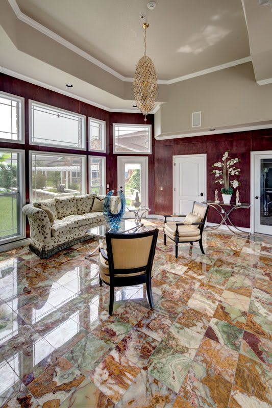 A luxurious living room with marble flooring, large windows, and elegant furnishings.
