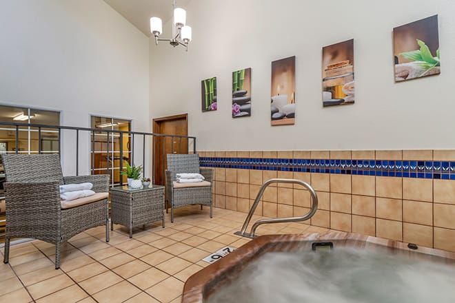 A tranquil indoor spa area featuring a jacuzzi, comfortable seating, and decorative wall art.