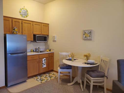 Cozy kitchen and dining area with wooden cabinets, a round table, and two chairs.