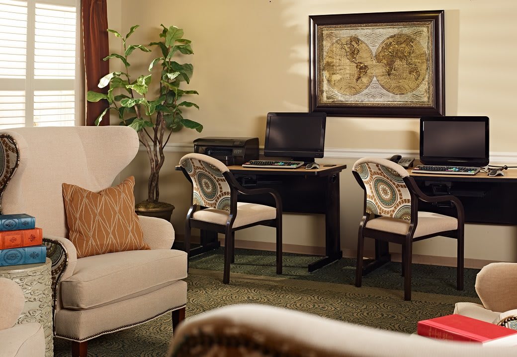 A cozy office space featuring desks with computers, comfortable chairs, and decorative plants.