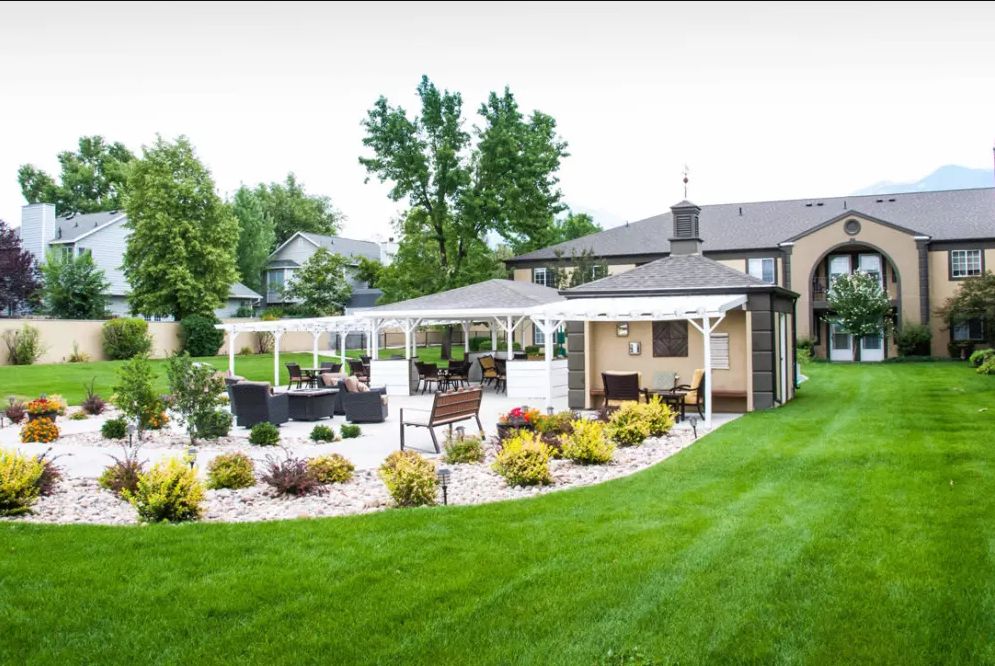 A beautifully landscaped backyard featuring a lush green lawn, an elegant patio with seating, and vibrant garden plants.