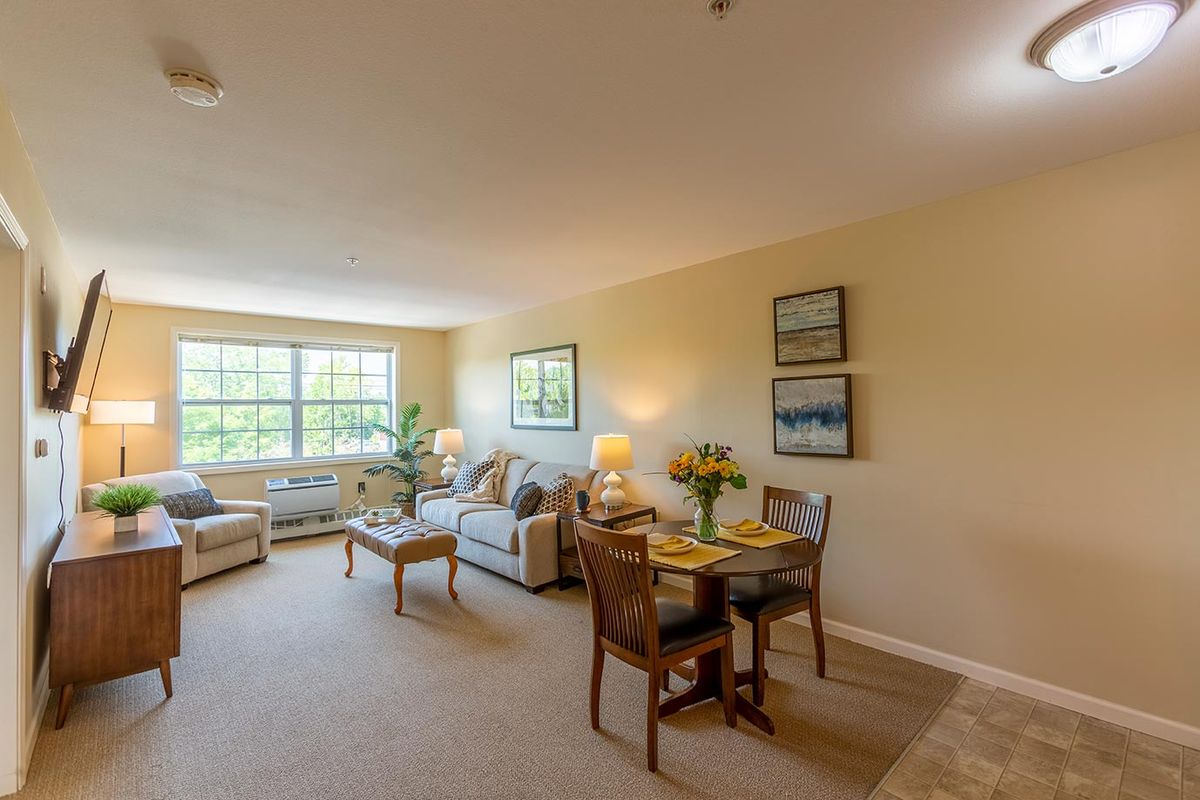 A cozy living room with a dining area, featuring comfortable furniture and large windows.