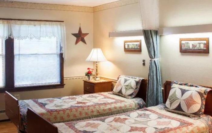 A cozy bedroom with twin beds featuring quilted bedspreads and a decorative star on the wall.