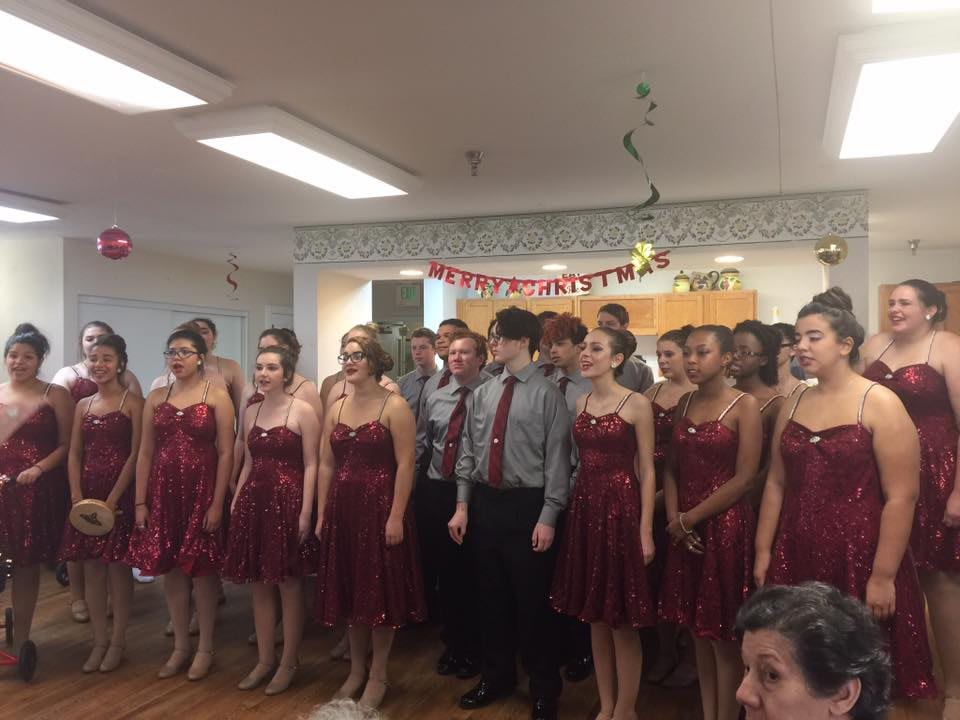 A choir group performs in formal attire at an indoor event.