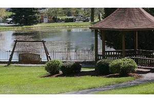 A serene garden scene featuring a gazebo, swing, and a lake in the background.