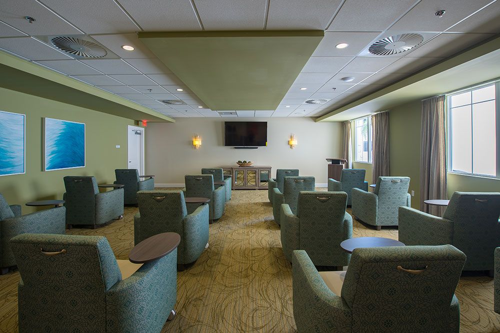 A well-lit lounge with multiple chairs facing a mounted television, ideal for meetings or group gatherings.