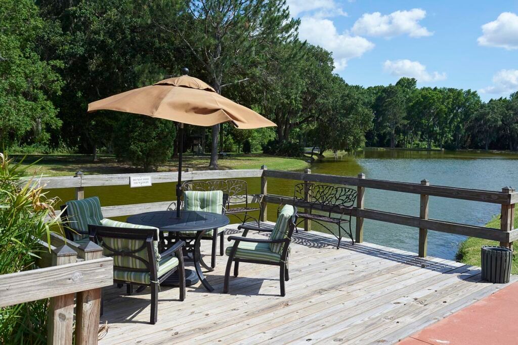 A scenic deck overlooking a lake, furnished with an umbrella and outdoor seating.