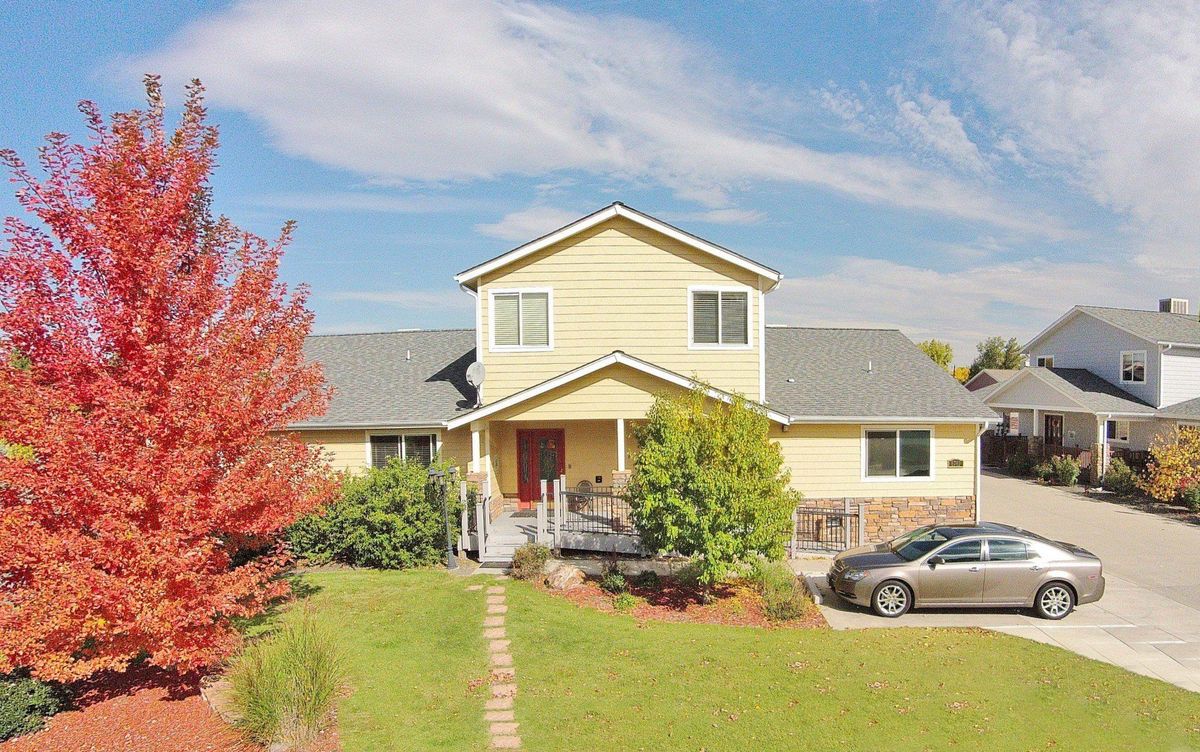 A two-story suburban house with a well-maintained front yard and a car parked in the driveway.