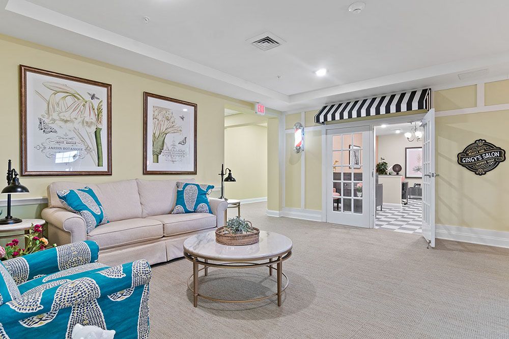 A cozy living room with a beige sofa, blue and white accents, artwork on the walls, and a striped awning over a doorway.