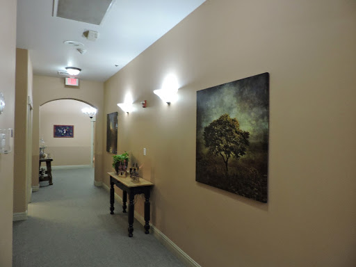 A serene hallway showcasing a piece of art on the wall, complemented by ambient lighting and a decorative table.