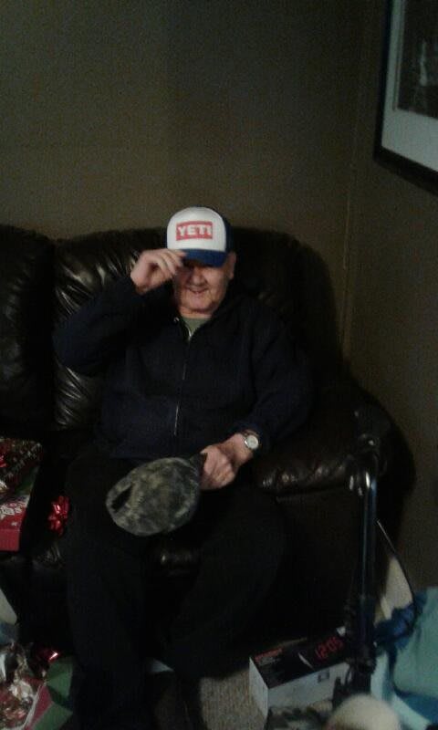 A person sitting on a couch indoors, adjusting their cap.