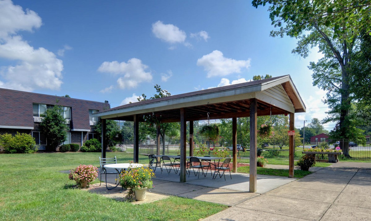 An outdoor pavilion with tables and chairs set under a clear blue sky.