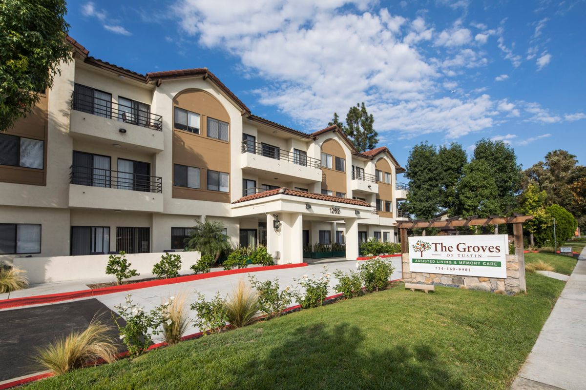 A modern residential building with well-maintained landscaping under a partly cloudy sky.