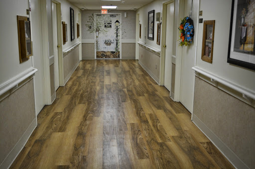 A well-lit interior hallway featuring wooden flooring and decorative wall frames.