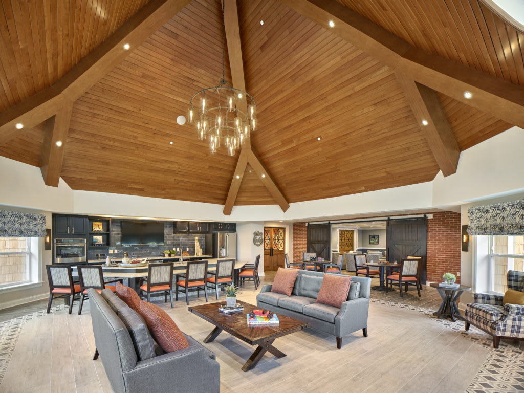 A spacious living room with a wooden ceiling and modern furniture.