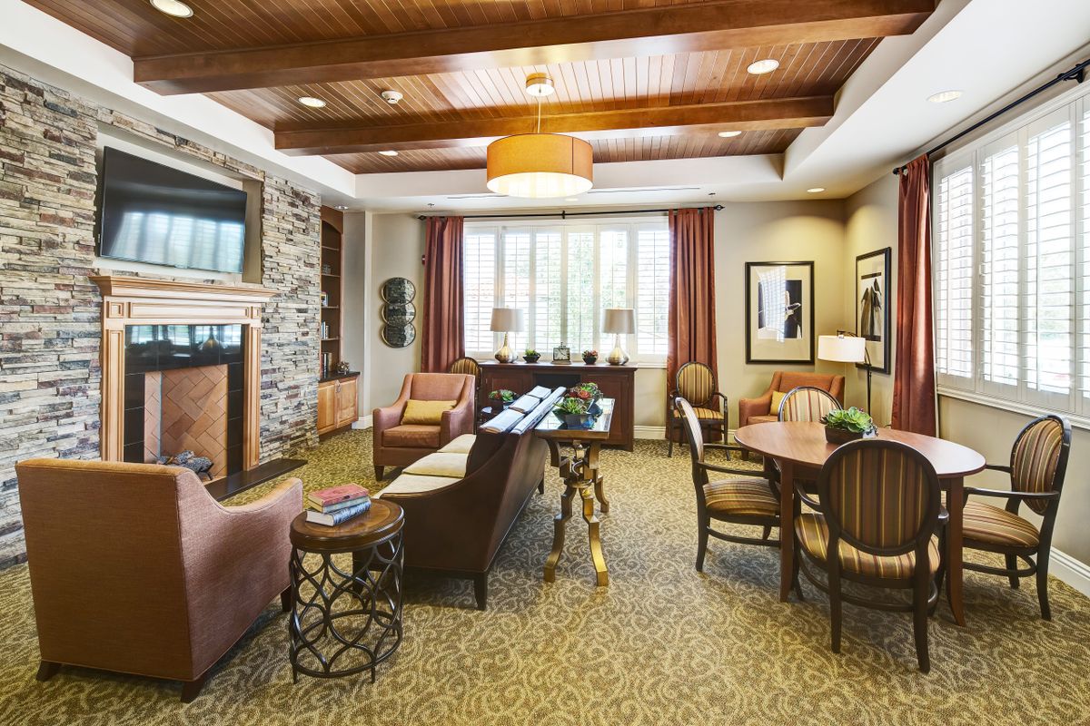 A cozy living room with modern decor, featuring a wood beam ceiling, comfortable seating, and a stylish fireplace.