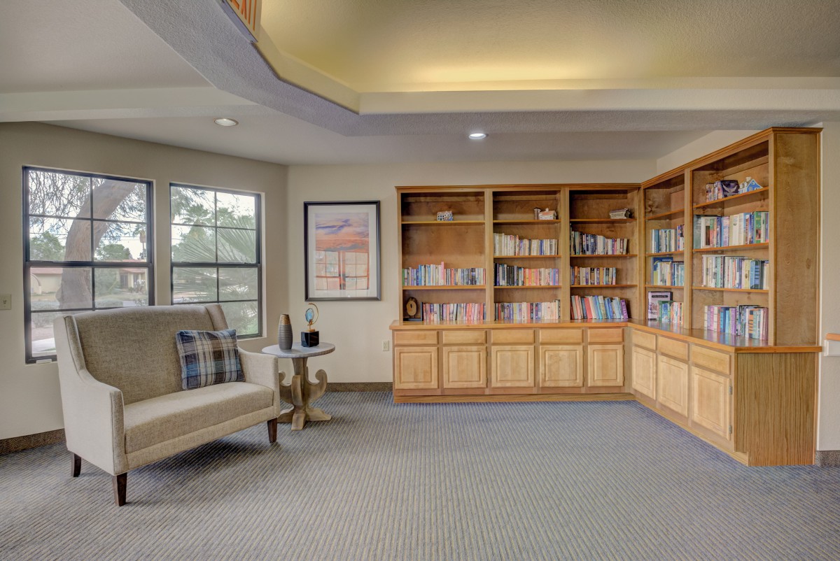 A cozy library room featuring wooden bookshelves, a comfortable seating area, and soft lighting.