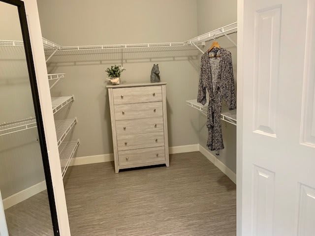 A neatly organized walk-in closet with a dresser and clothing racks.