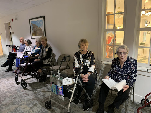 A group of seniors gathered in a community space, waiting and socializing.