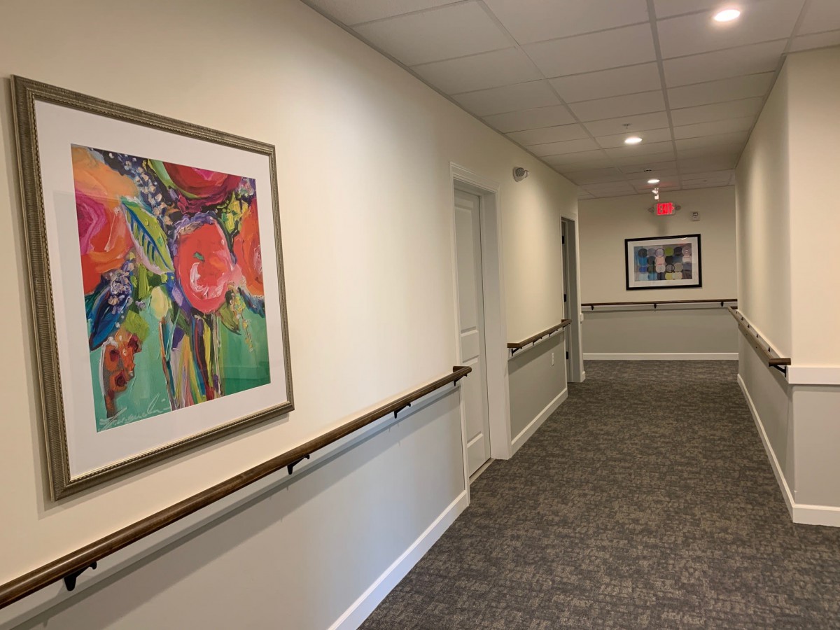 A hallway with colorful paintings and handrails, featuring an exit sign.