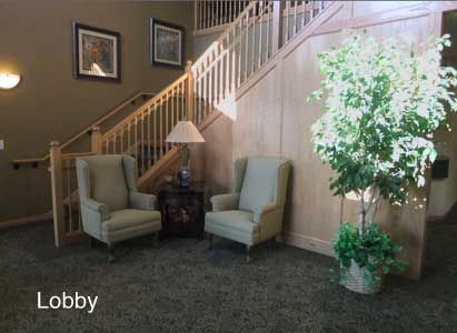 A cozy lobby area with two armchairs, a lamp, and a potted plant near a staircase.