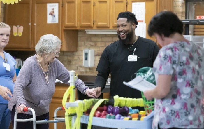 A healthcare worker interacts with elderly residents during an activity session.