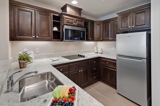 Modern kitchen with dark wood cabinetry and stainless steel appliances.