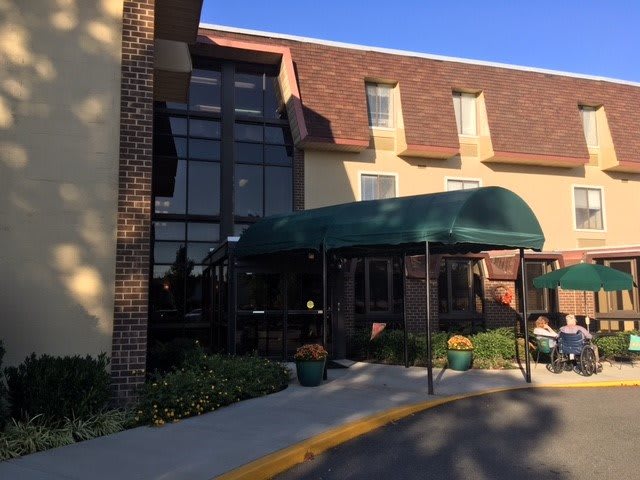 The entrance of a building with a green awning and large windows.