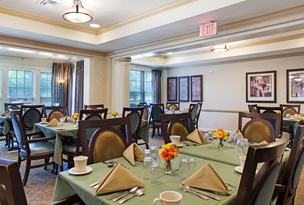 A well-set dining room with neatly arranged tables and chairs, featuring elegant decor and soft lighting.