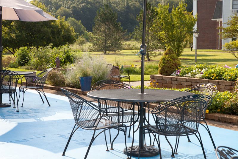 A serene outdoor patio with metal furniture overlooking a lush garden landscape.