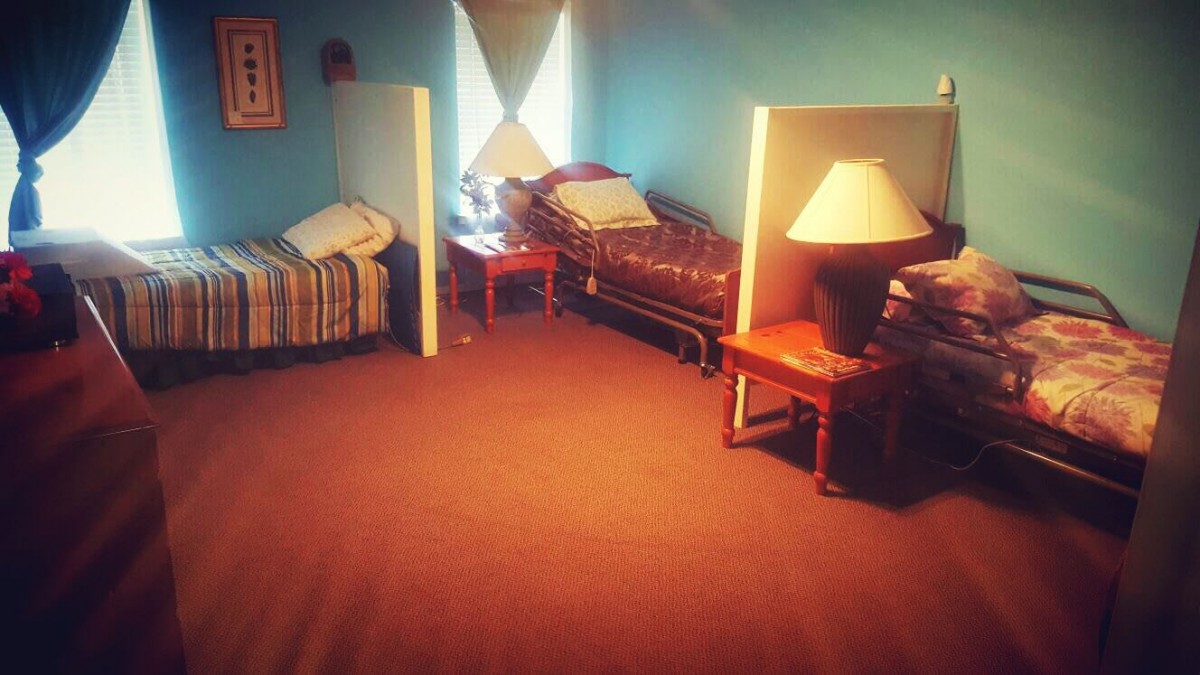 A cozy bedroom with two beds separated by partitions, featuring a lamp on a nightstand.