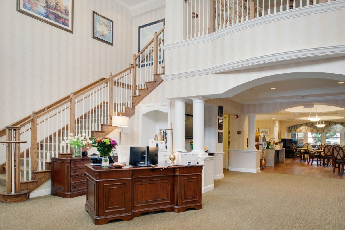 A well-designed office reception area with a wooden desk, staircase, and elegant decor.
