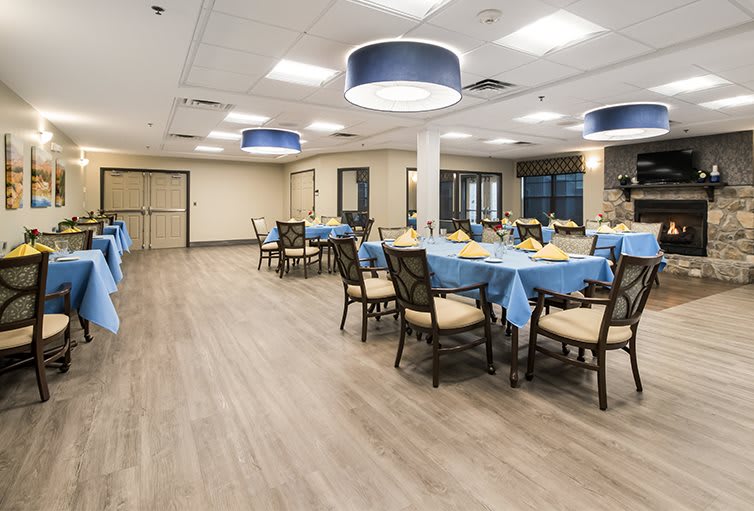 A spacious dining area with tables covered in blue tablecloths and comfortable seating.