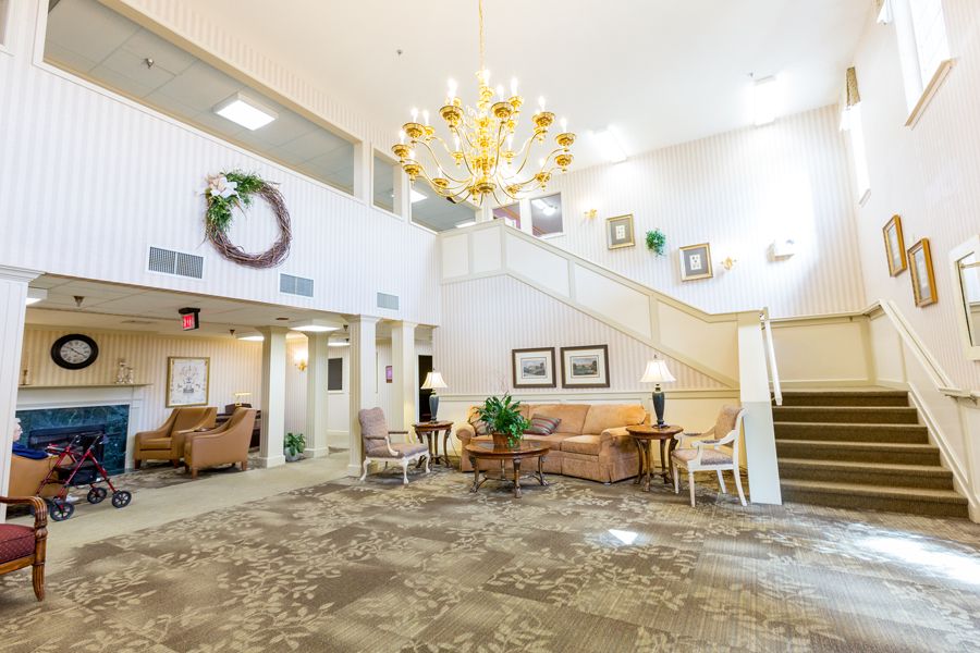 A spacious and elegantly decorated lobby with a large chandelier, seating area, and staircase.